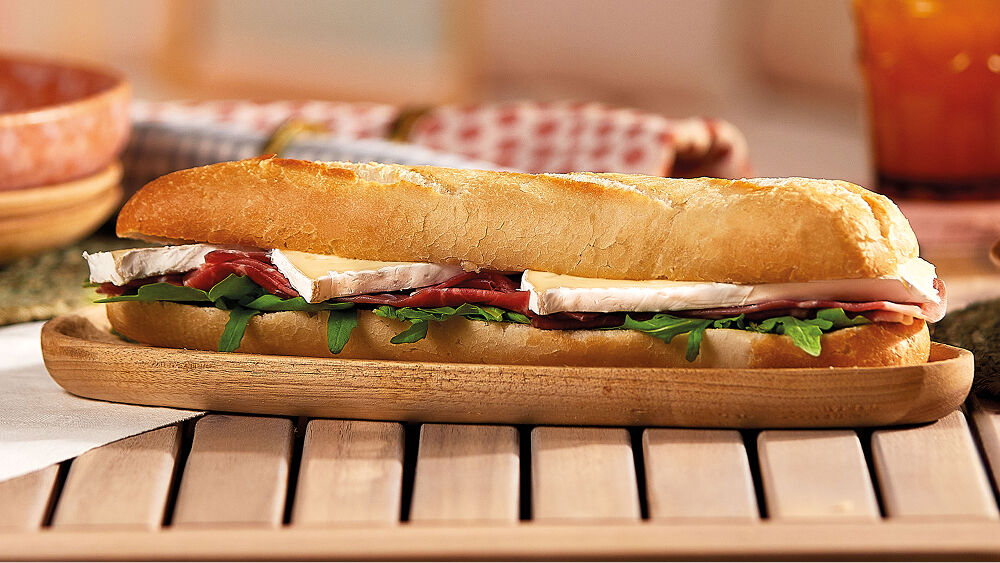 Fotografia de uma baguete de r&uacute;cula, presunto e queijo brie